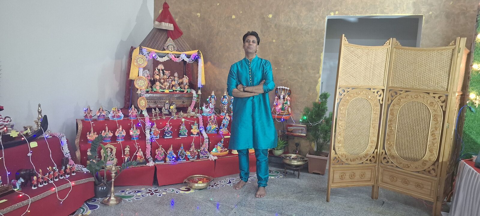 Capt. Prabhu in a blue kurta beside a traditional Indian doll display.