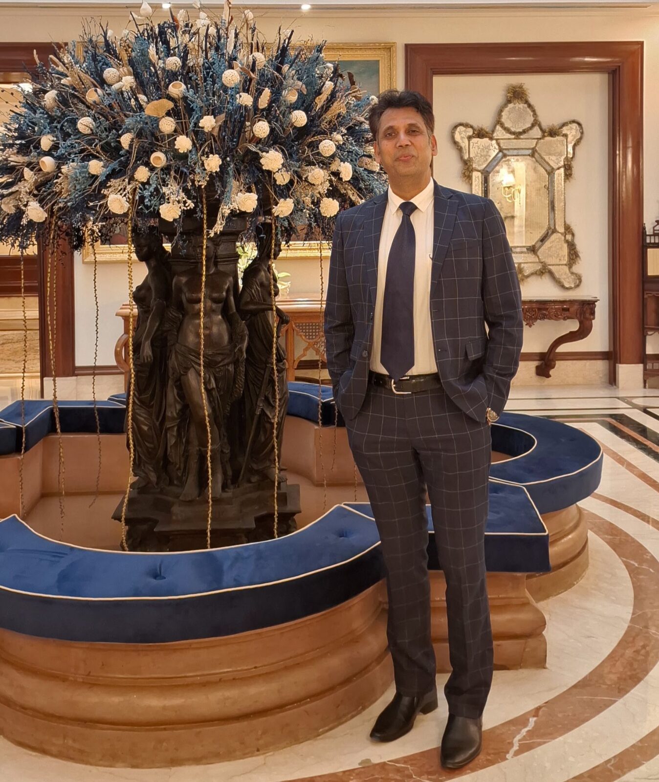 Capt. Prabhu in a tailored navy suit at a luxury hotel lobby in New Delhi.